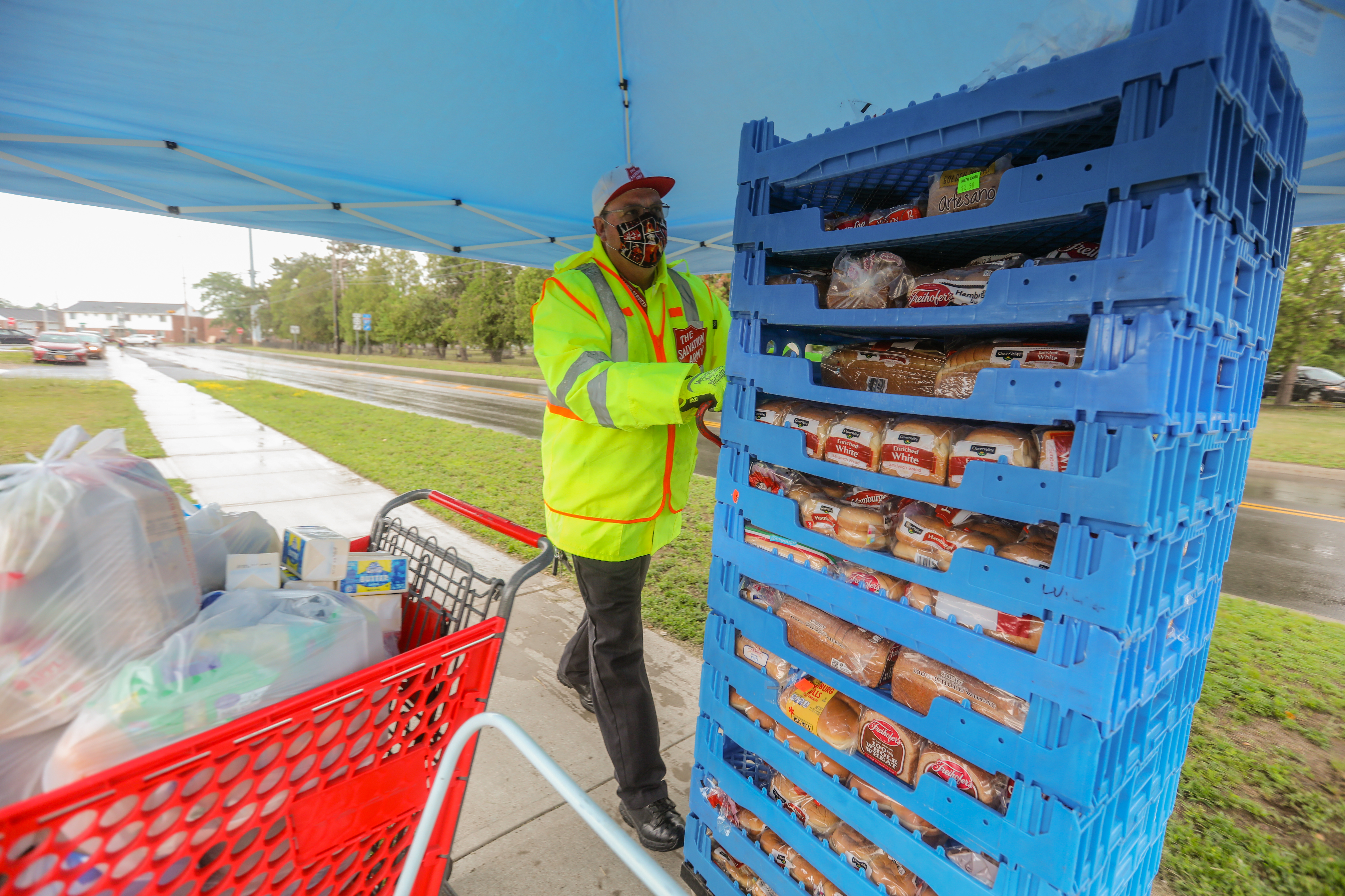 A man wearing a mask pushes a cart with food. 