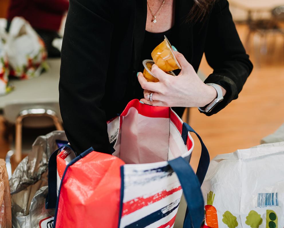 Hands packing a food backpack for a student in Indian Lake